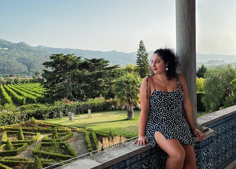 woman sitting on balcony edge facing garden Sintra Portugal