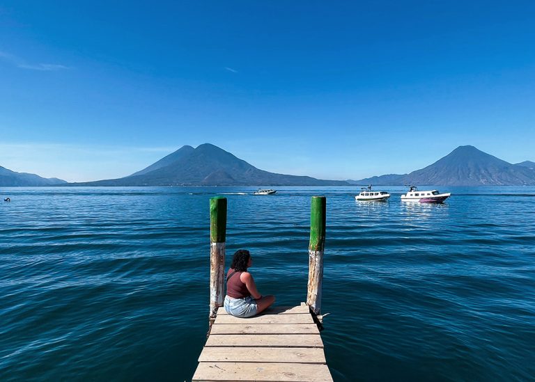 woman sitting on dock edge at Lake Atitlán