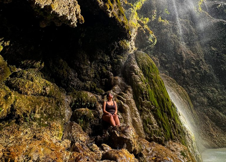 woman sitting under tropical waterfall