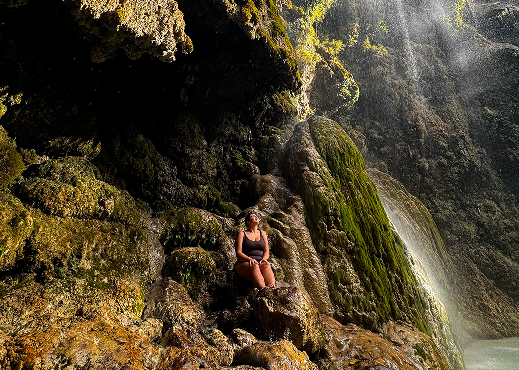 woman sitting under tropical waterfall