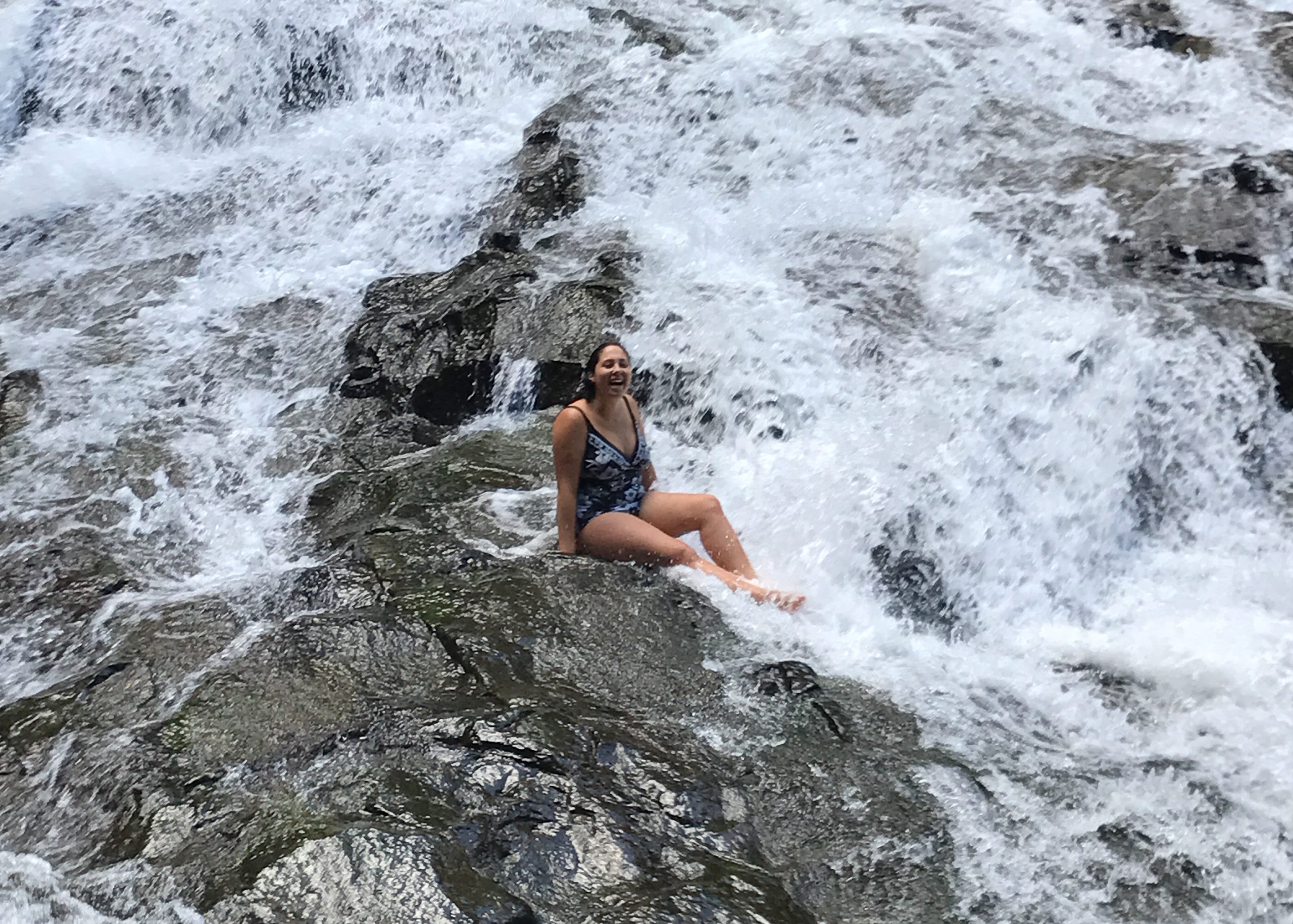 woman sitting on rock in waterfall