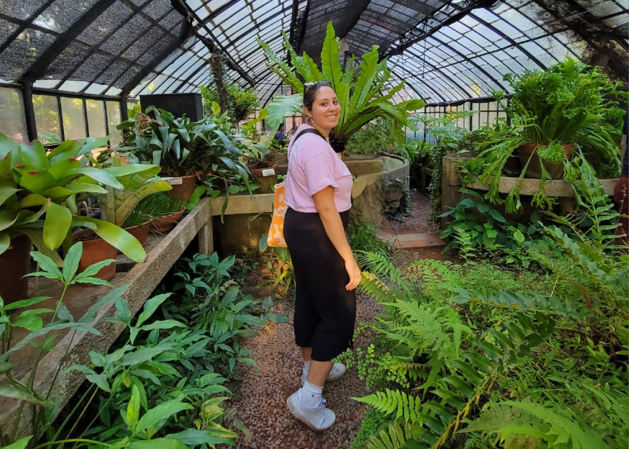woman walking in greenhouse full of green plants