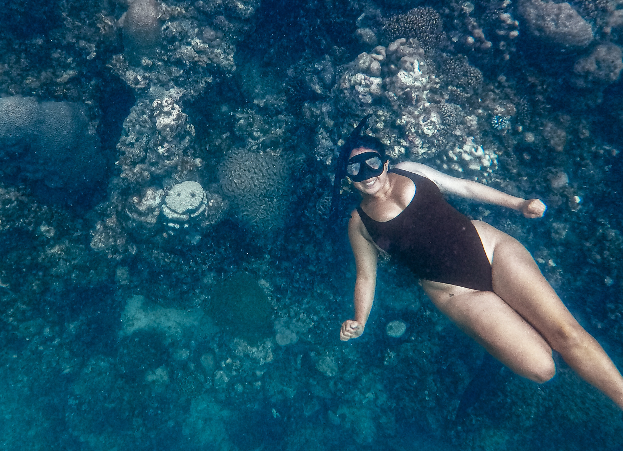 woman freediving beside smiling reef