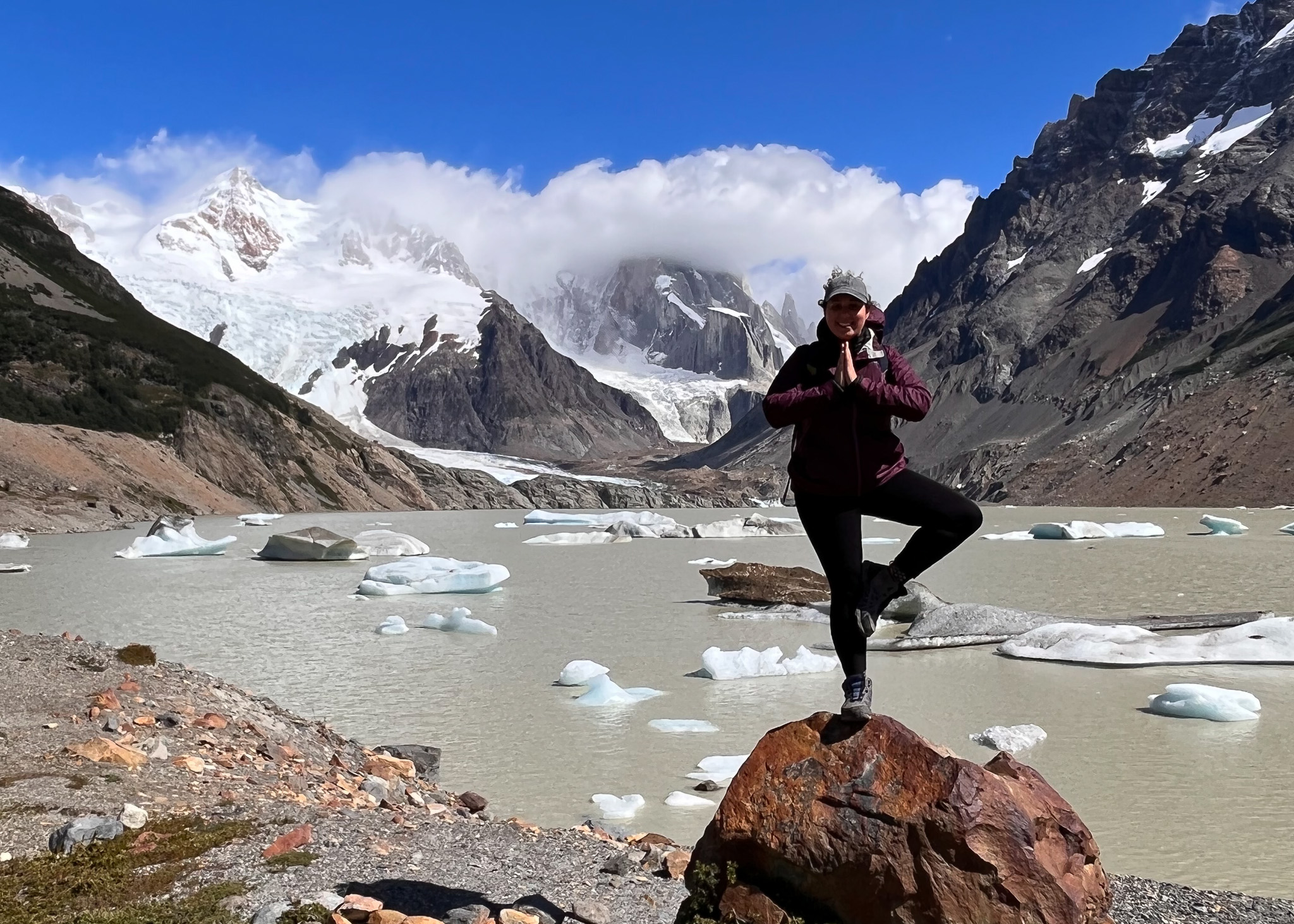 woman doing yoga on rock in front of mountain view