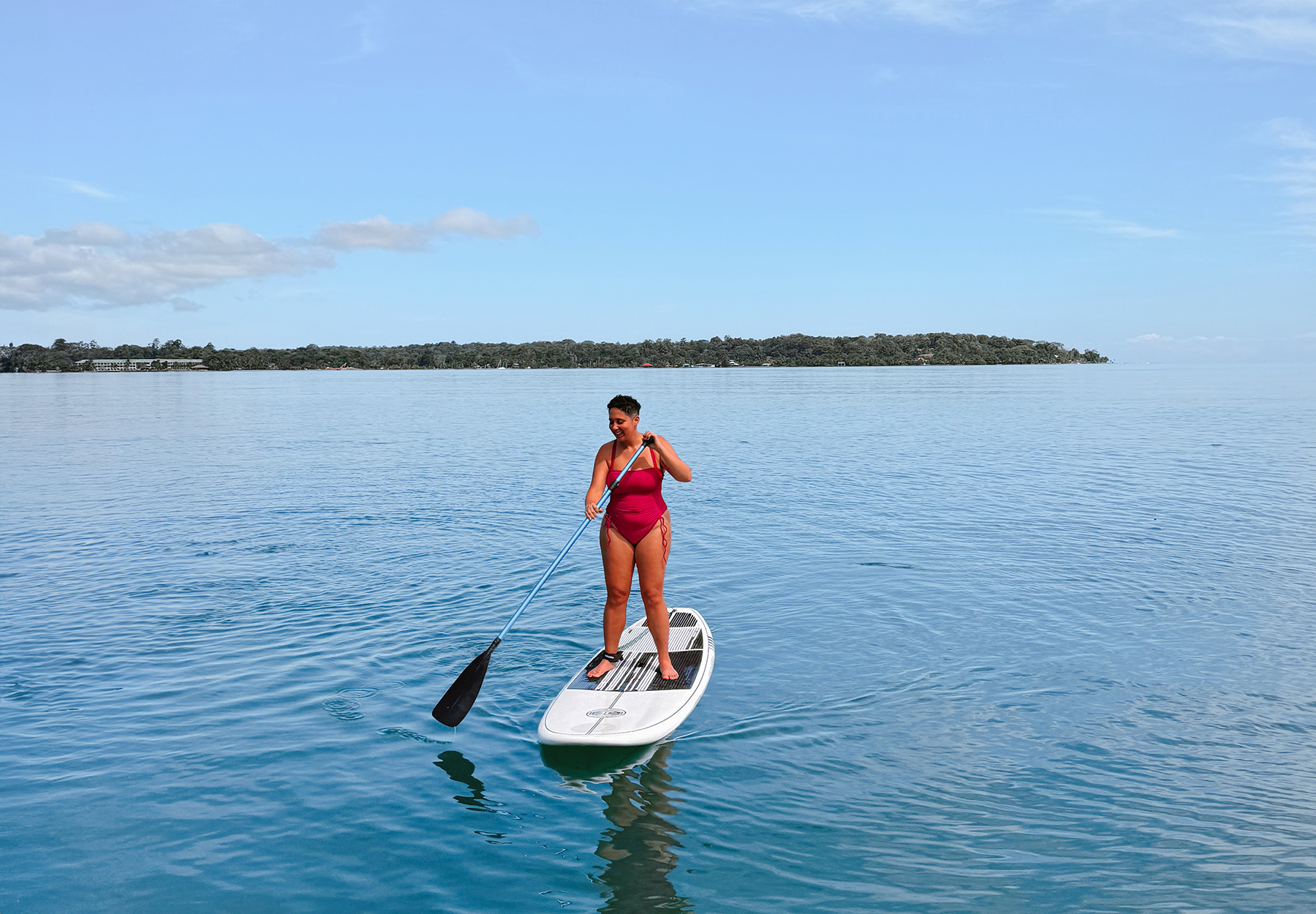 woman paddle boarding on flat blue Caribbean Sea