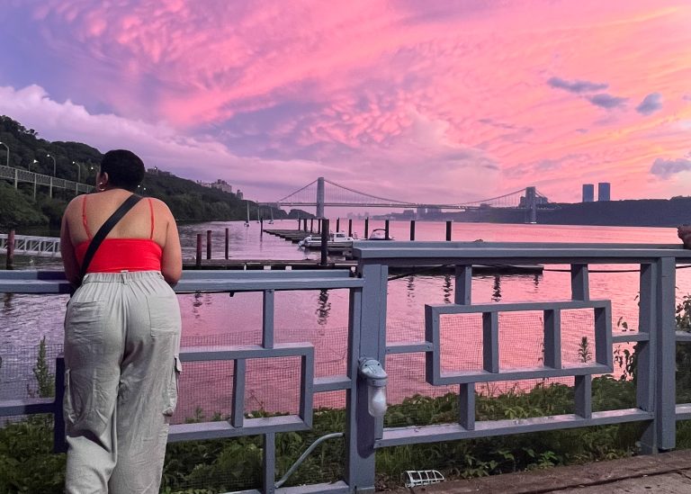 woman standing by pink sky and New York City background