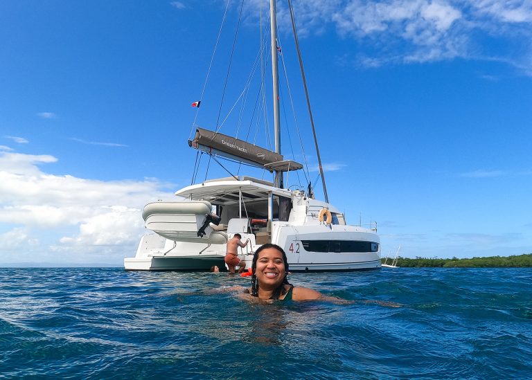 Woman smiling in front of Dream Yacht Charter Catamaran sailing in Belize